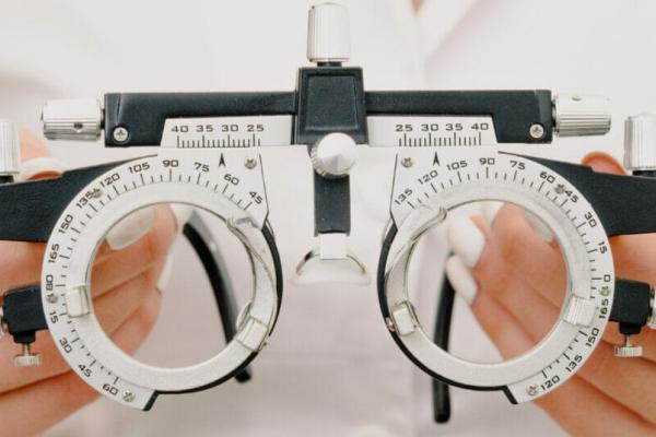 Crop unrecognizable female optometrist with trial frame in hands