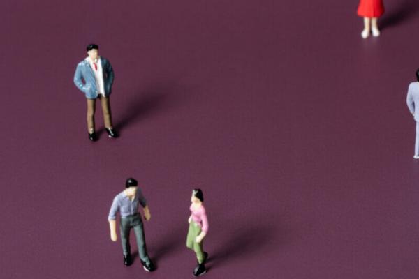 Five miniature figurines of people against a dark purple background. Two figurines look to be having a conflict and the other three are standing separate from each other.