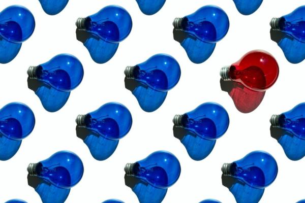 A pattern of lightbulbs against a white background - all the lightbulbs are blue except one that is red