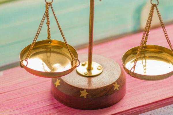 An empty brass scale on a wooden rainbow striped table