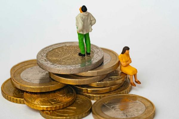 Man and woman sitting on unequal levels of coins