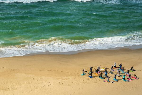 A group of people doing well-being yoga on a beach