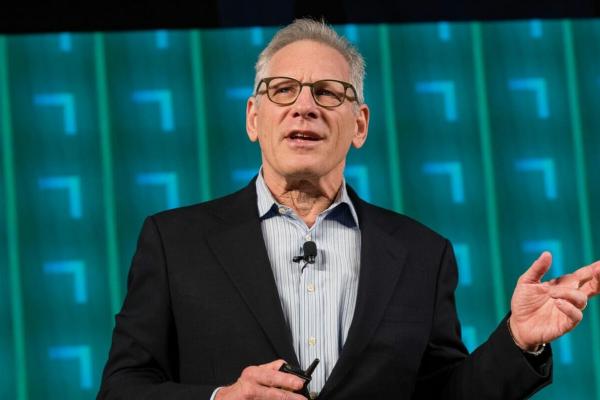 Image of Stew Friedman wearing a black suit jacket and light blue shirt in front of a teal blue background