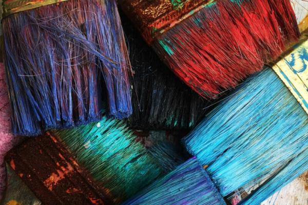 Several rainbow paintbrushes on a rainbow background showing diversity