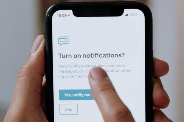 A phone with someone choosing if they should turn on notifications, commanding the user's attention