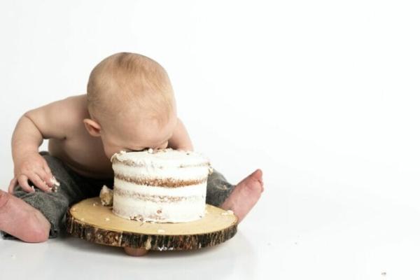 An image of a baby smashing its face into a cake to celebrate the anniversary of "Baby Bust," a book about balancing work and life.